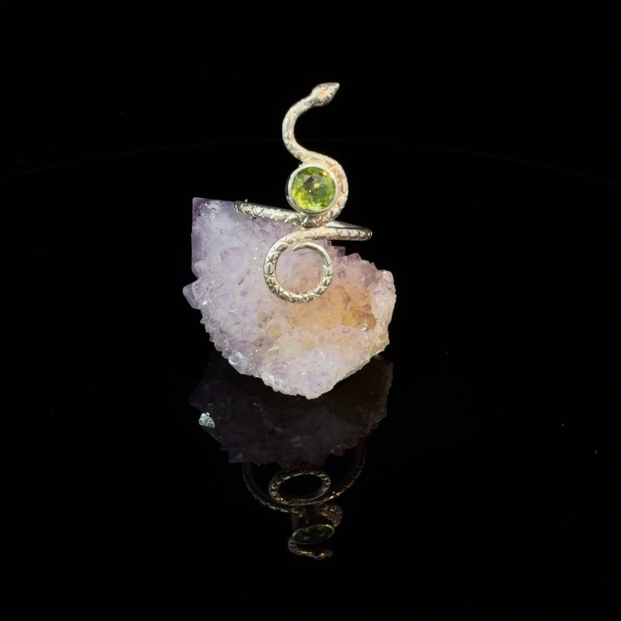 Handcrafted sterling silver snake ring featuring a natural round Peridot gemstone with a textured serpent band, size 6.75.