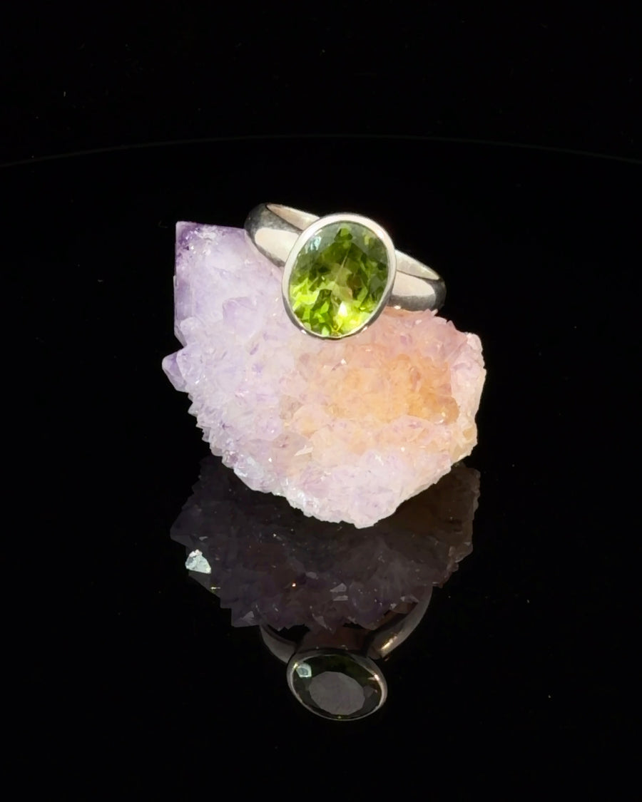 Natural oval Peridot bezel set sterling silver solitaire ring size 6.5 with vibrant green gemstone on polished silver band.