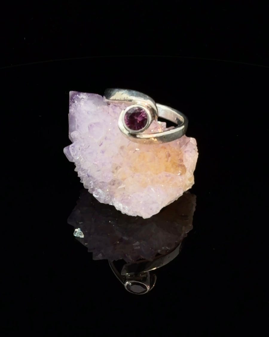 Handcrafted sterling silver bypass ring featuring a natural bezel-set Pink Garnet solitaire gemstone, modern swirl design, size 7.25.