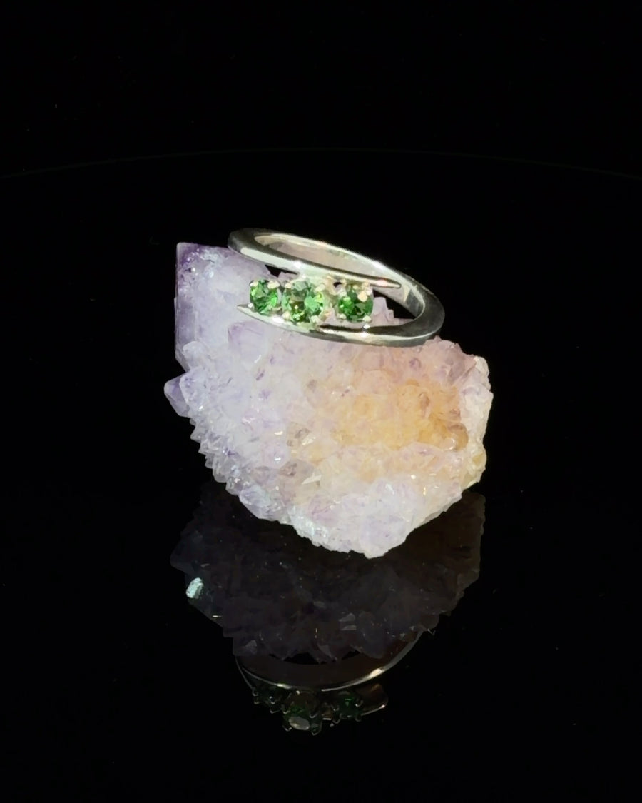 Sterling silver bypass ring featuring three natural green Tsavorite Garnets in a modern asymmetrical three-stone design.