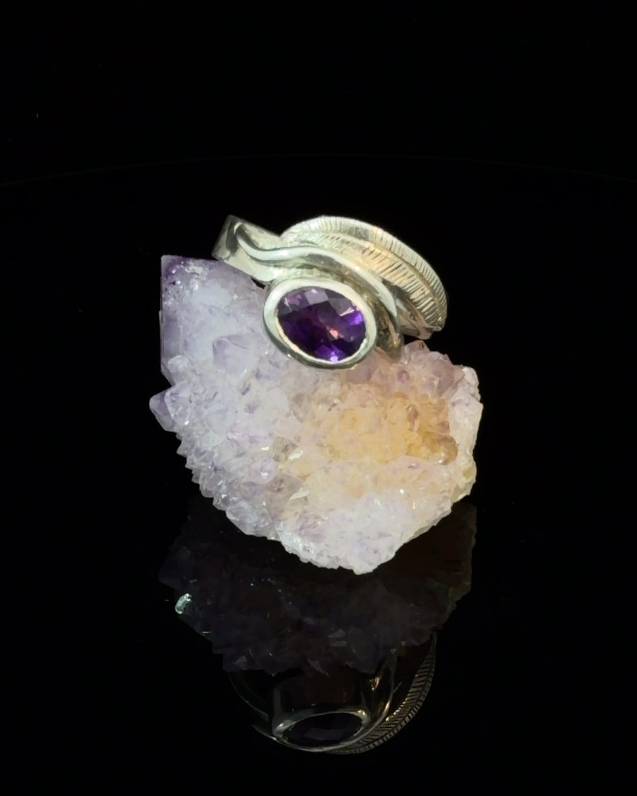 Handcrafted sterling silver feather ring featuring a bezel set faceted natural Amethyst gemstone on a wide textured band, size 7.75.
