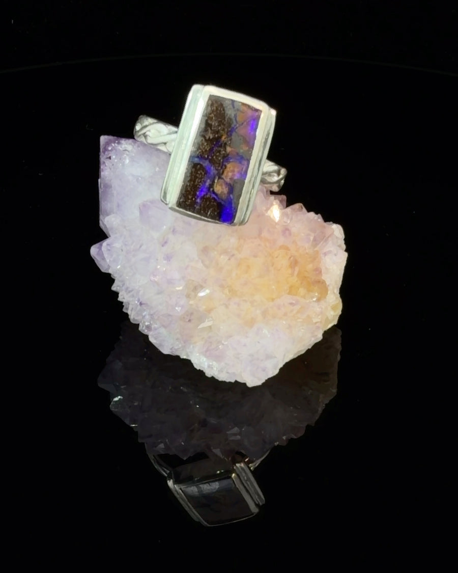 Natural Australian Black Opal solitaire ring in sterling silver featuring vivid blue and purple flashes in a rectangular bezel-set gemstone with a textured twist band, size 6.