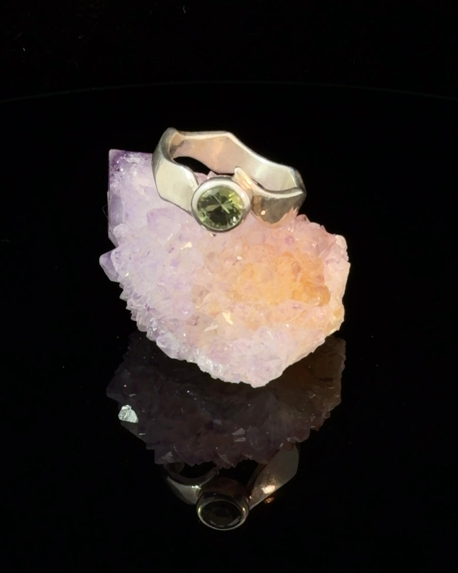 a handcrafted sterling silver solitaire ring featuring a natural faceted Green Tourmaline in a secure bezel setting.