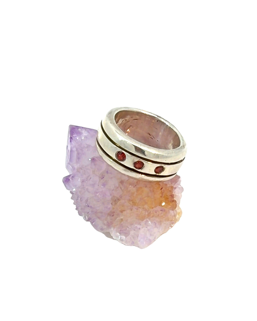 Handcrafted sterling silver ring featuring three natural round garnets in an engraved band. Size 7