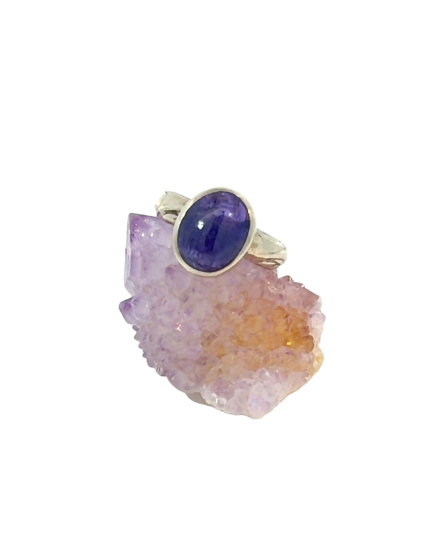 a handcrafted sterling silver Tanzanite ring featuring a natural deep purple oval cabochon in a smooth bezel setting.