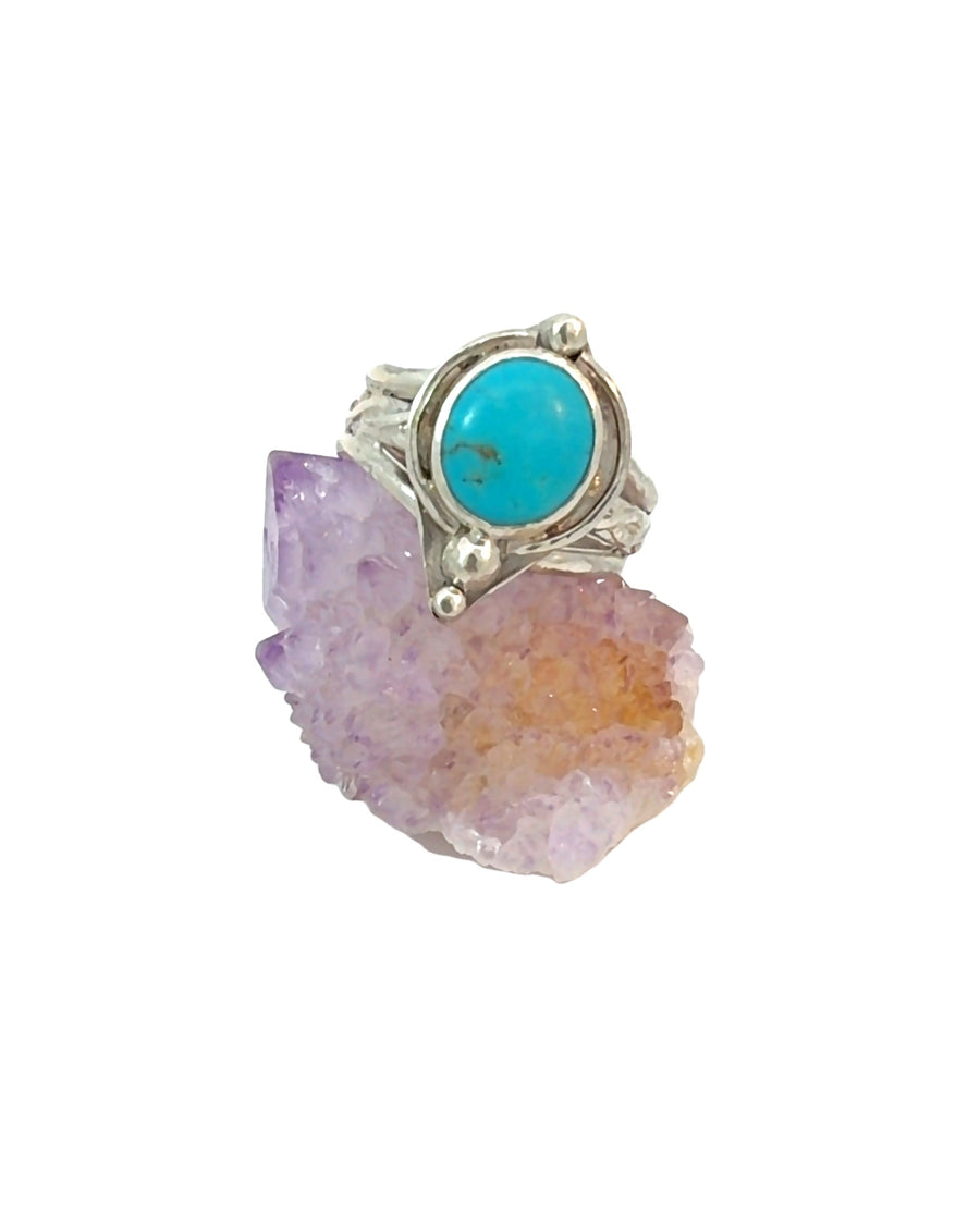 Handcrafted sterling silver ring featuring a natural turquoise cabochon in a smooth bezel setting with decorative silver bead accents and a textured band, size 10.