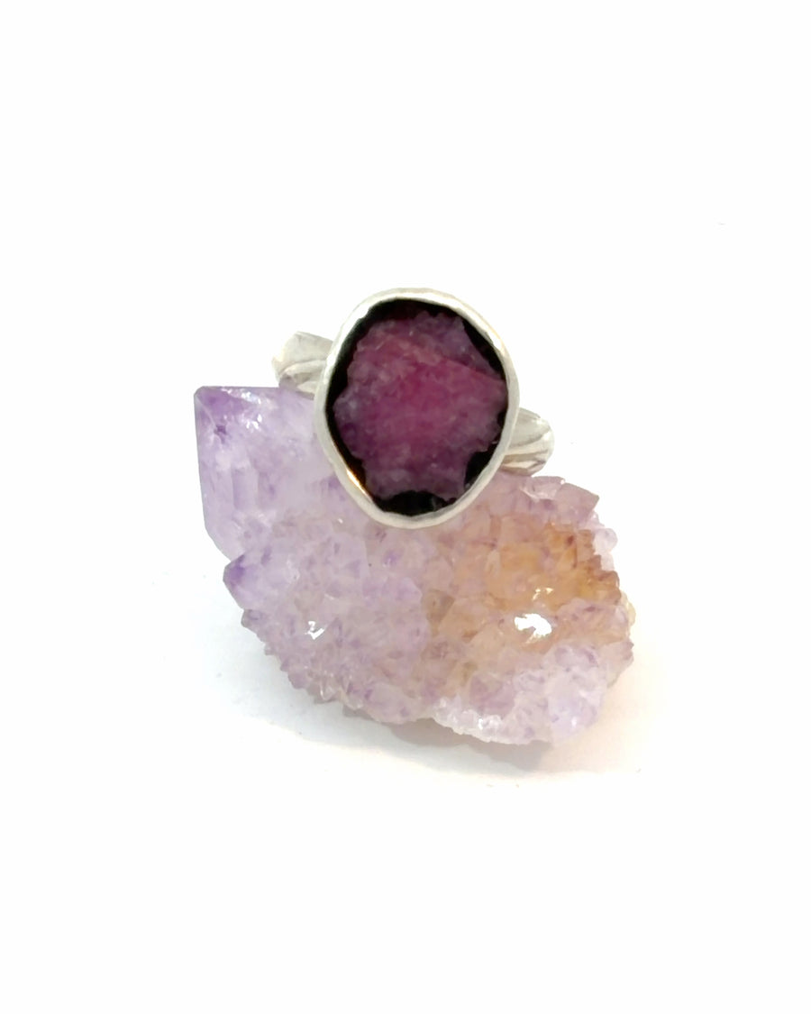 Handmade sterling silver solitaire ring featuring a natural purplish red raw ruby in a textured bezel setting, size 8.