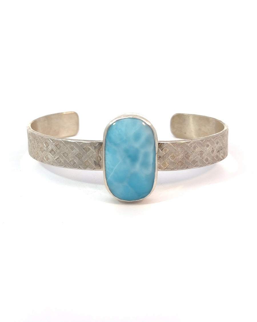 Handmade sterling silver cuff bracelet featuring a large natural oval Larimar cabochon with ocean-blue color, white marbling, woven textured band, and bezel setting.