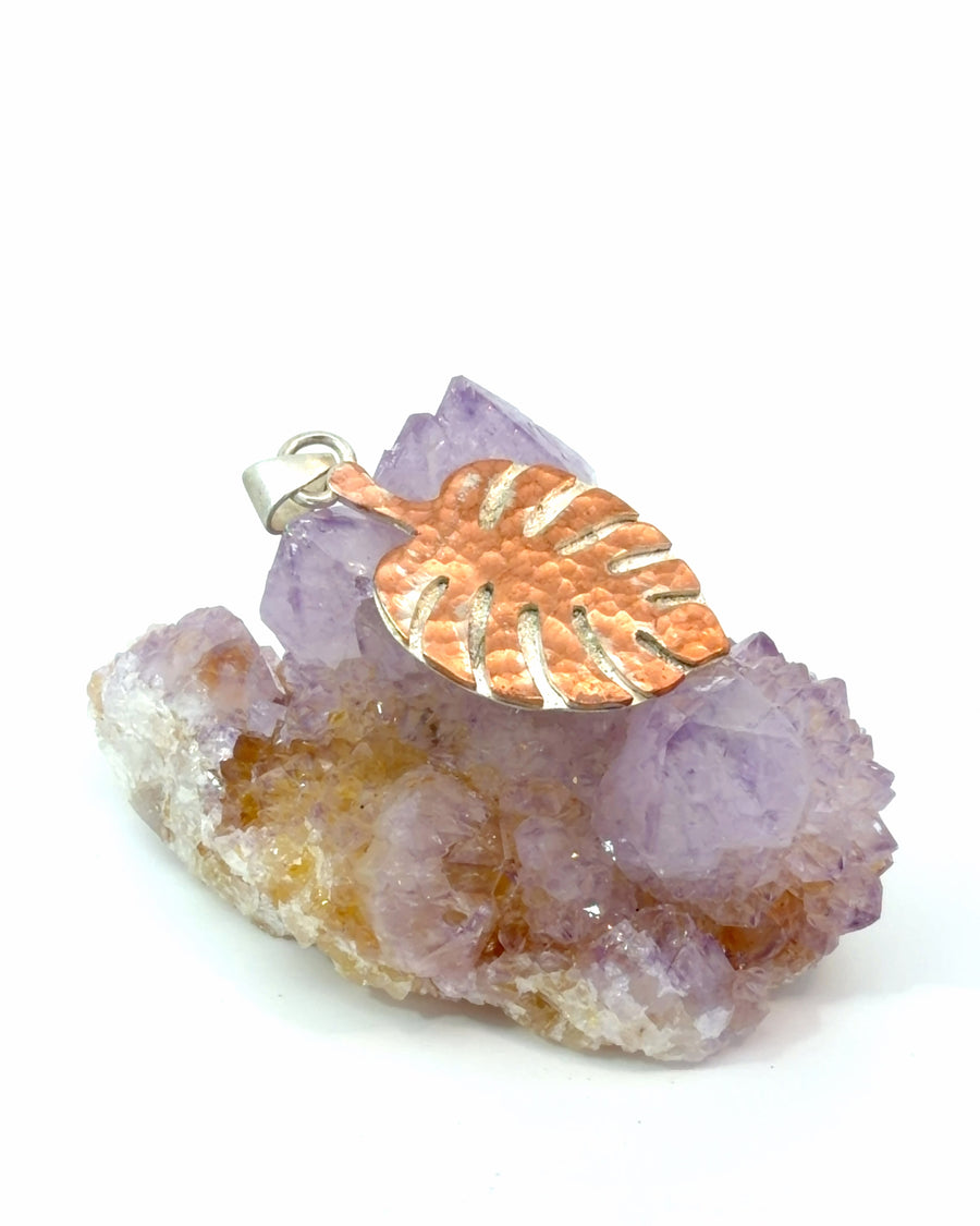 Mixed metal Monstera leaf pendant with hammered copper center, silver border, and intricate botanical cutout design.
