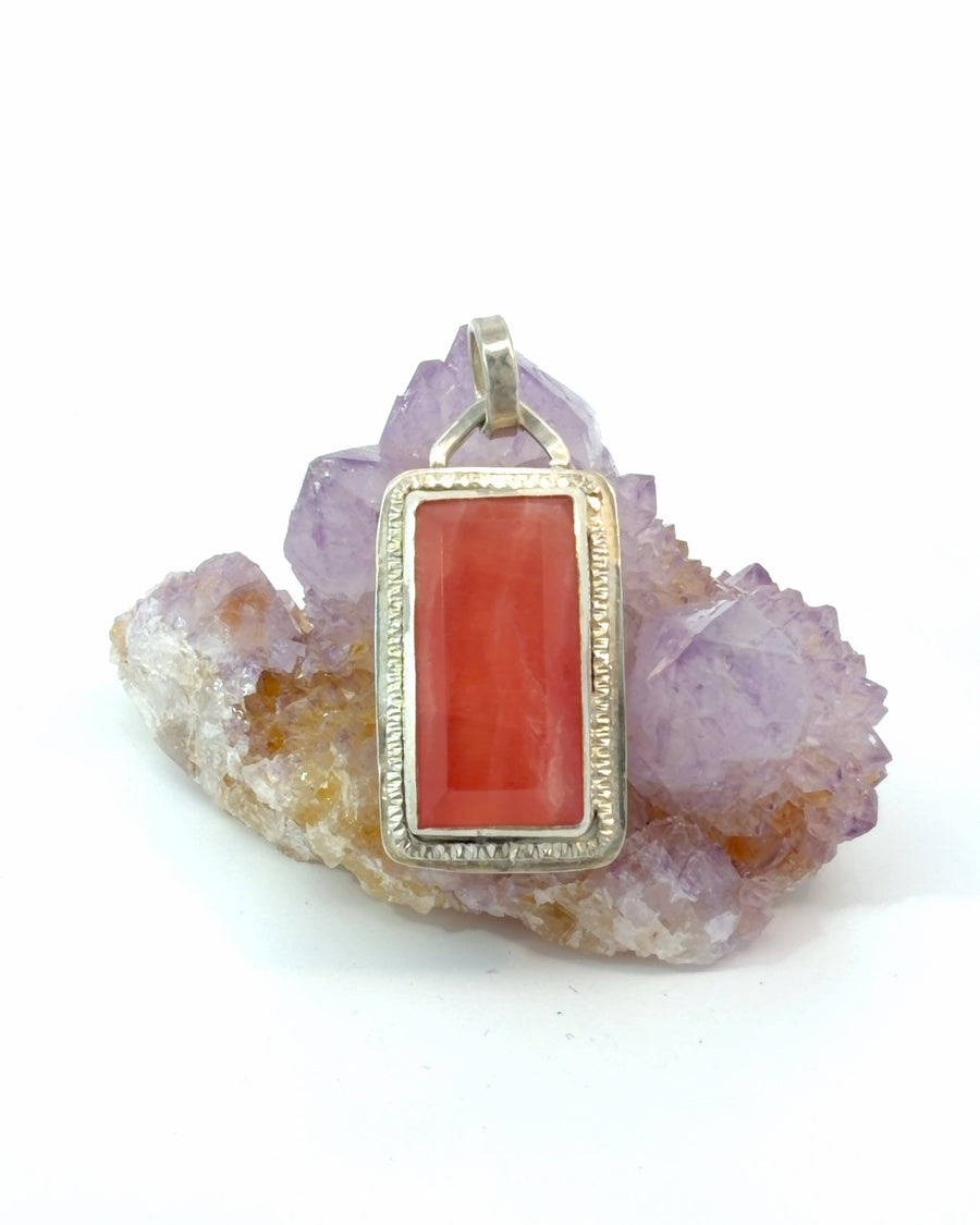 Handmade sterling silver pendant featuring a rectangular natural rhodochrosite gemstone in a textured bezel setting with an articulated bail.