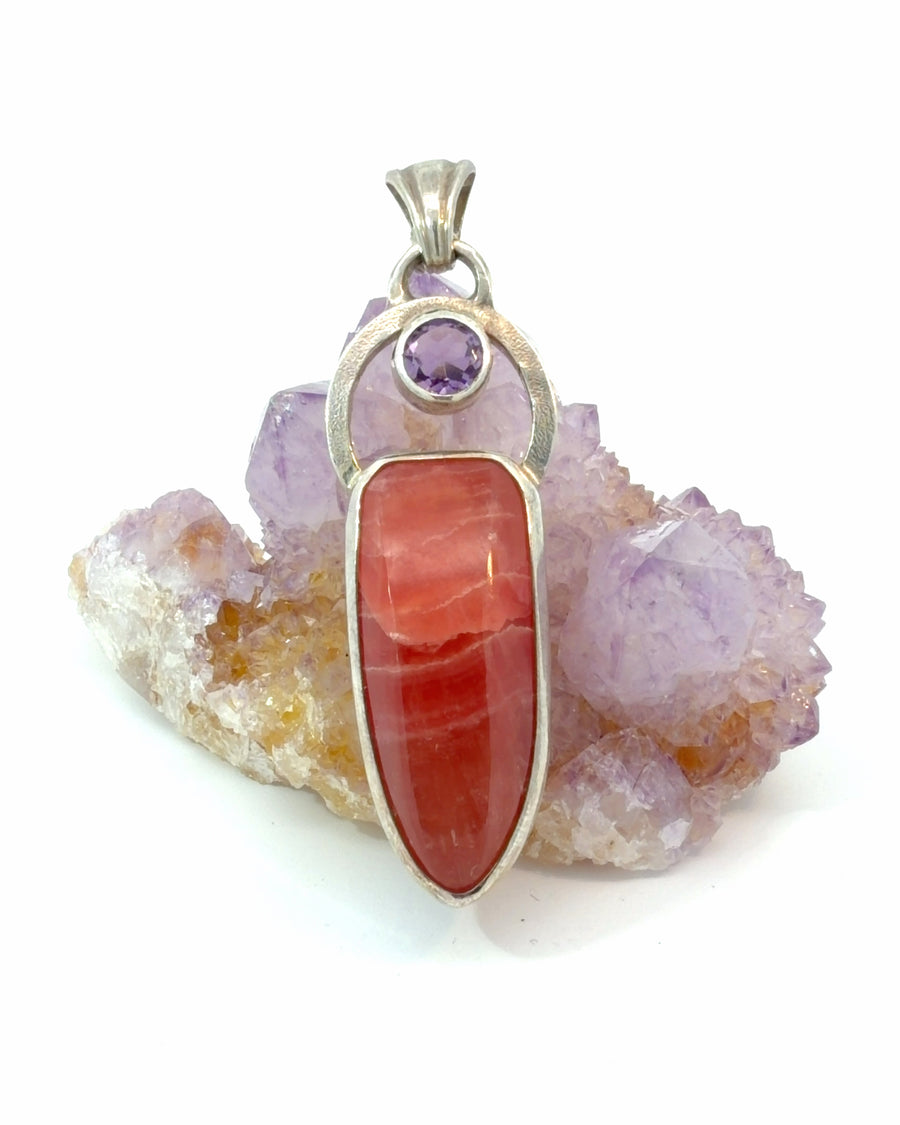 Handcrafted sterling silver pendant featuring a natural Rhodochrosite cabochon with a round faceted Amethyst accent.