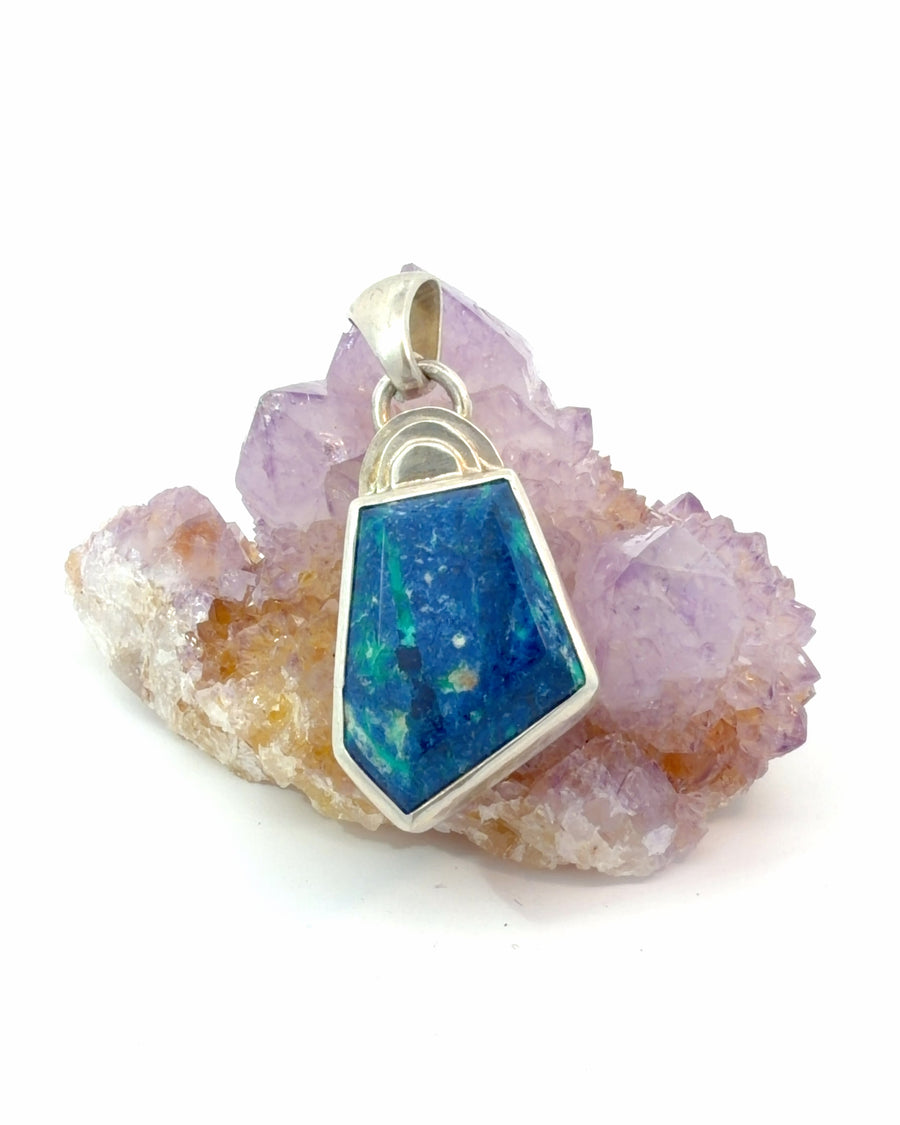 Natural geometric-cut azurite pendant in sterling silver with vibrant blue and green mineral patterns in a handcrafted bezel setting.