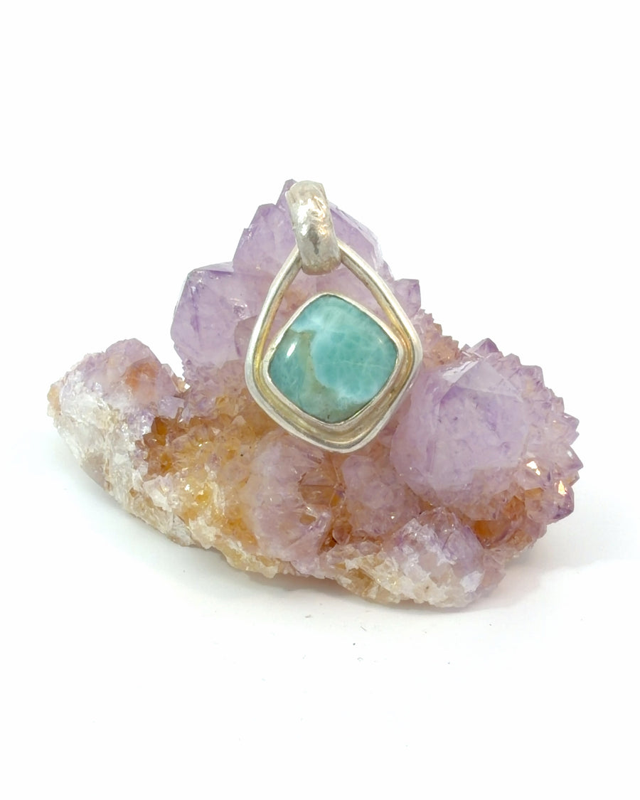 Handcrafted sterling silver pendant featuring a natural square Larimar cabochon in a polished bezel with an open teardrop frame.
