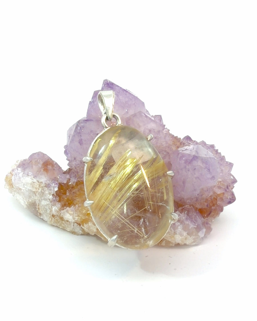 Handcrafted sterling silver pendant featuring a natural golden rutilated quartz cabochon with striking golden needle inclusions suspended within clear quartz.