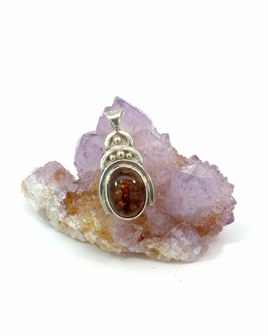 Handcrafted sterling silver pendant featuring a natural oval Fire Agate cabochon in a polished bezel setting with decorative silver bead accents.
