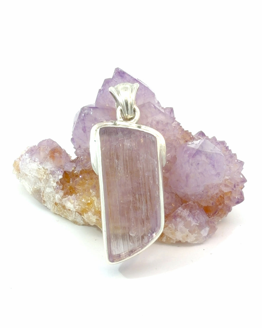 Natural kunzite slice pendant in sterling silver featuring raw pink-purple crystal with natural striations and handcrafted bezel setting.