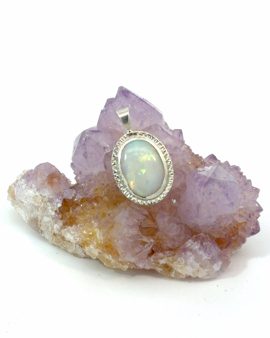 Oval natural opal pendant featuring vibrant flashes of color in a detailed silver bezel setting. Elegant handcrafted gemstone jewelry.
