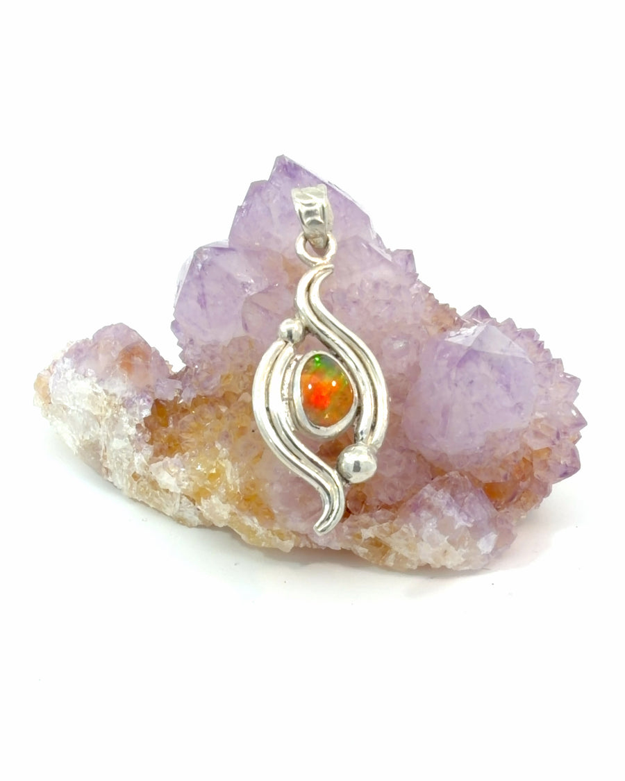 Polished silver pendant featuring a natural opal cabochon with vibrant green and orange flashes in an elegant wave-inspired design with silver bead accents.