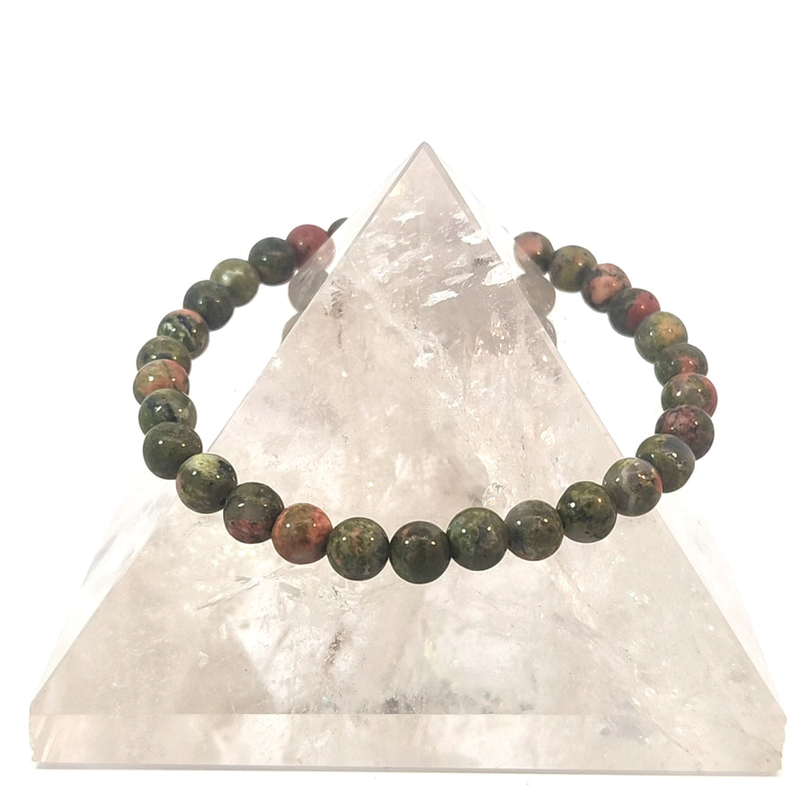 Wear a natural Unakite stretch bracelet featuring peach and green gemstone beads. Believed to promote emotional healing, balance, grounding, and personal growth.