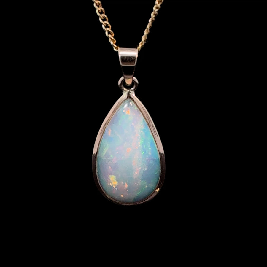 Natural Ethiopian opal teardrop pendant in solid 14K gold featuring vibrant flashes of red, orange, and green play-of-color.
