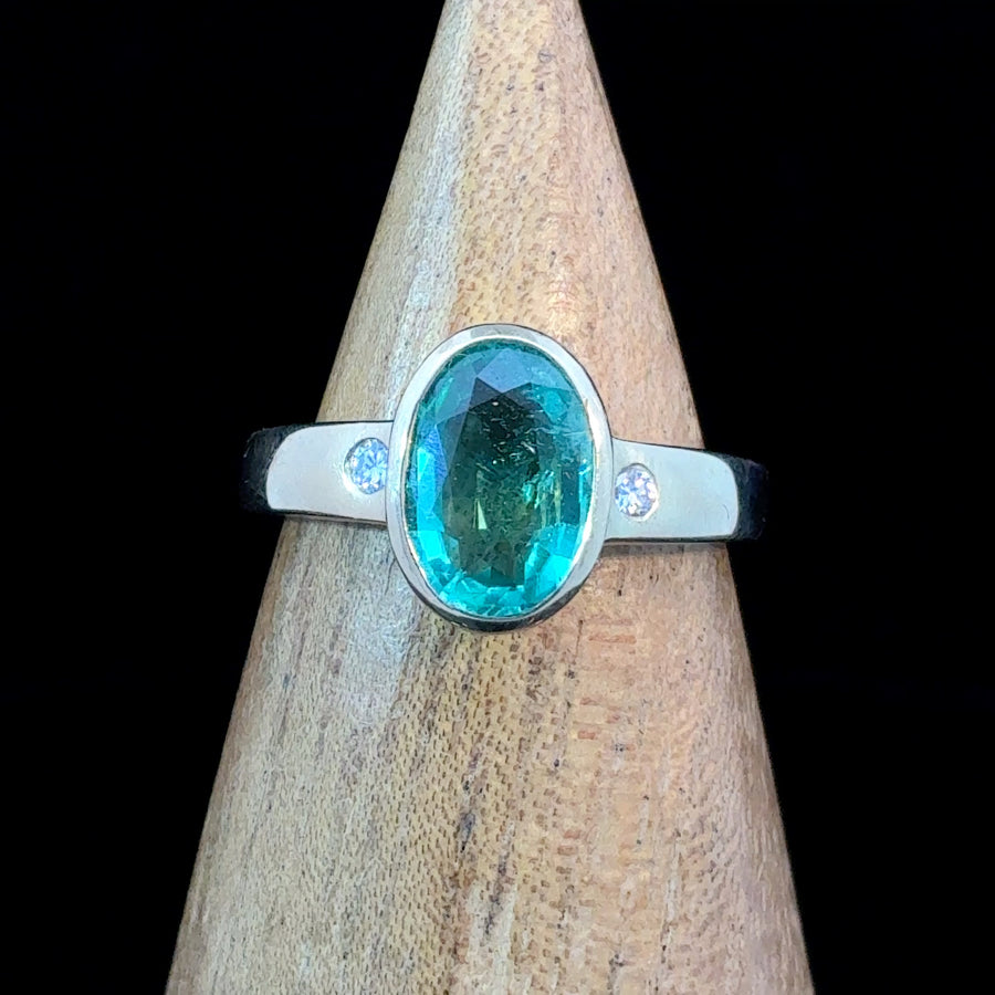 Large oval faceted emerald three-stone ring in 14K gold with two flush-set diamond accents, size 7.25.