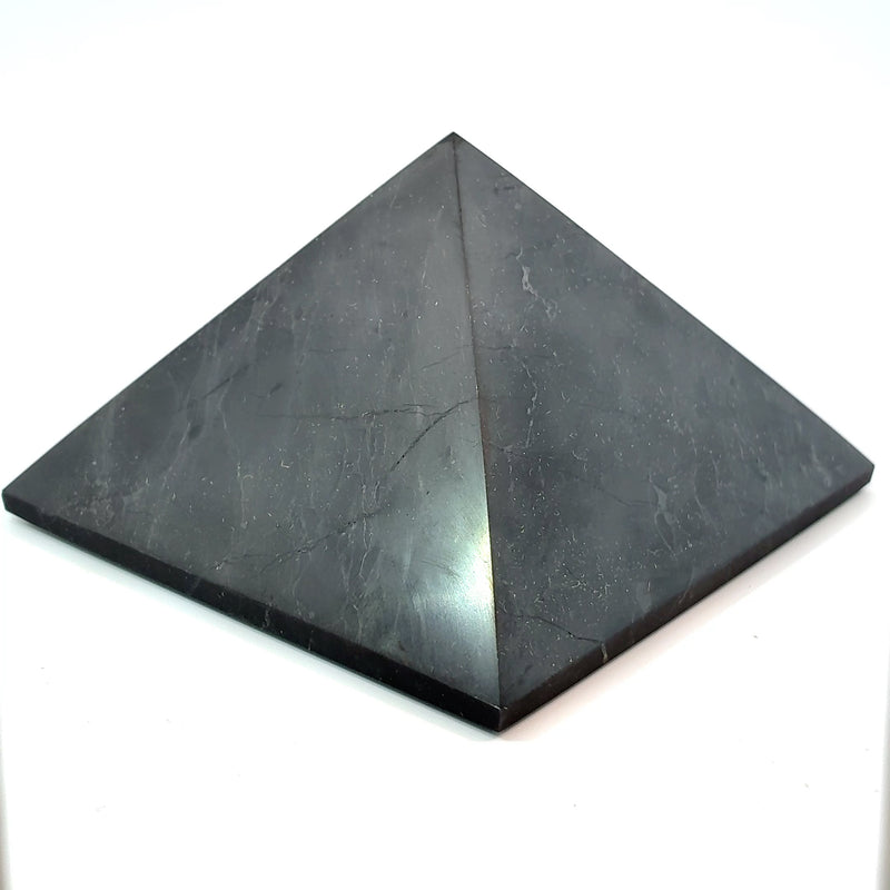 Natural polished Shungite pyramid from Russia measuring approximately 75 mm wide by 50 mm tall, black carbon-rich mineral for crystal collecting, meditation, and home décor.