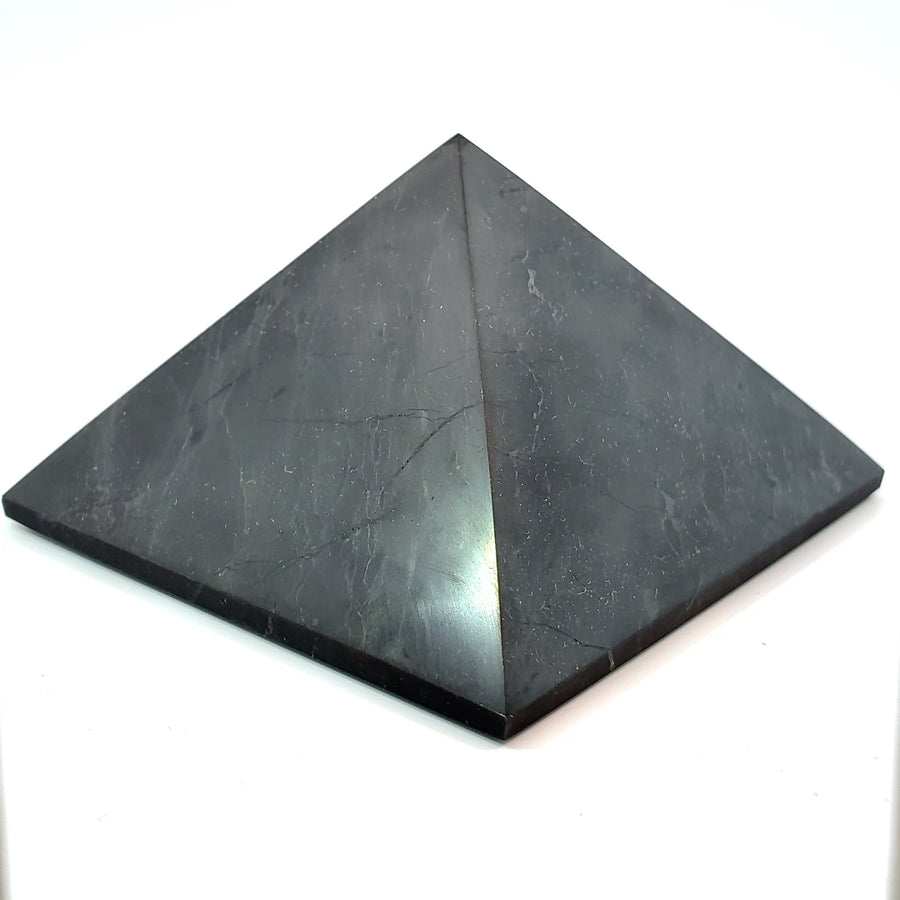 Natural polished Shungite pyramid from Russia measuring approximately 75 mm wide by 50 mm tall, black carbon-rich mineral for crystal collecting, meditation, and home décor.
