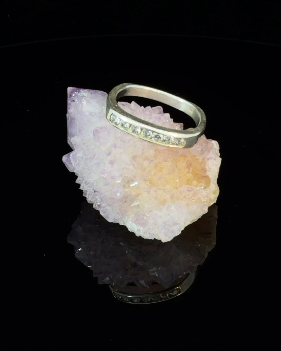 Squared sterling silver ring with seven channel-set cubic zirconia stones on a crystal display